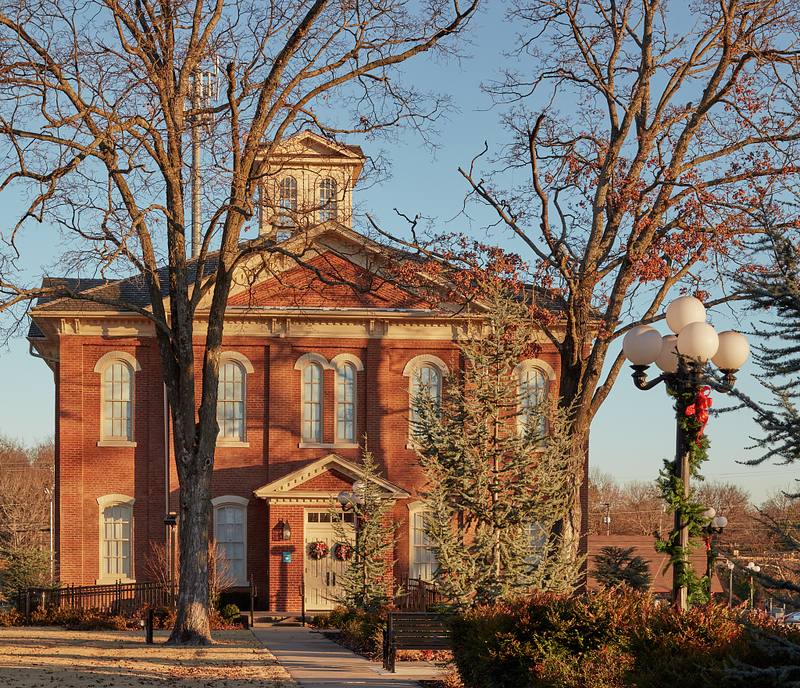 The red-brick Cherokee National Capitol and its white cupola, framed by bare trees in evening light