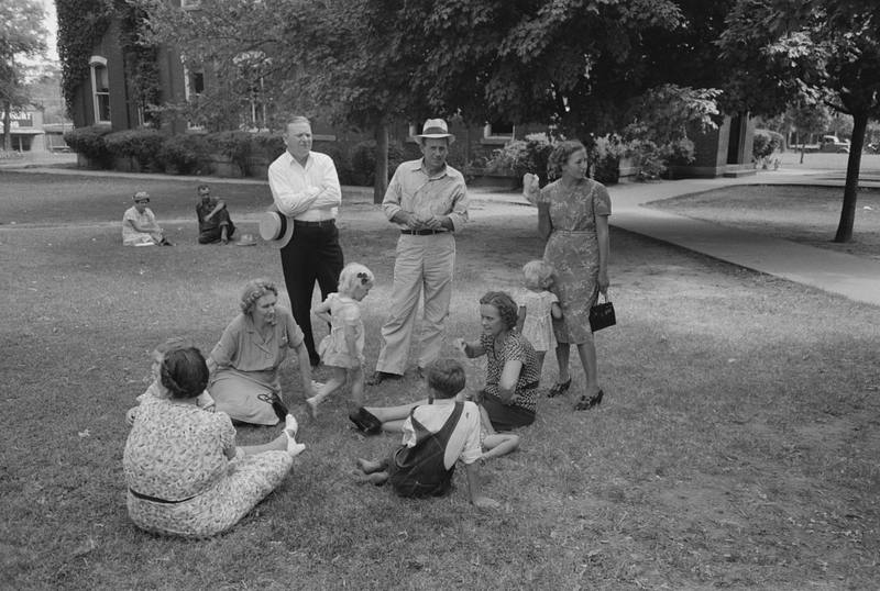 Families sitting and standing on the courthouse lawn on a summer day in 1939